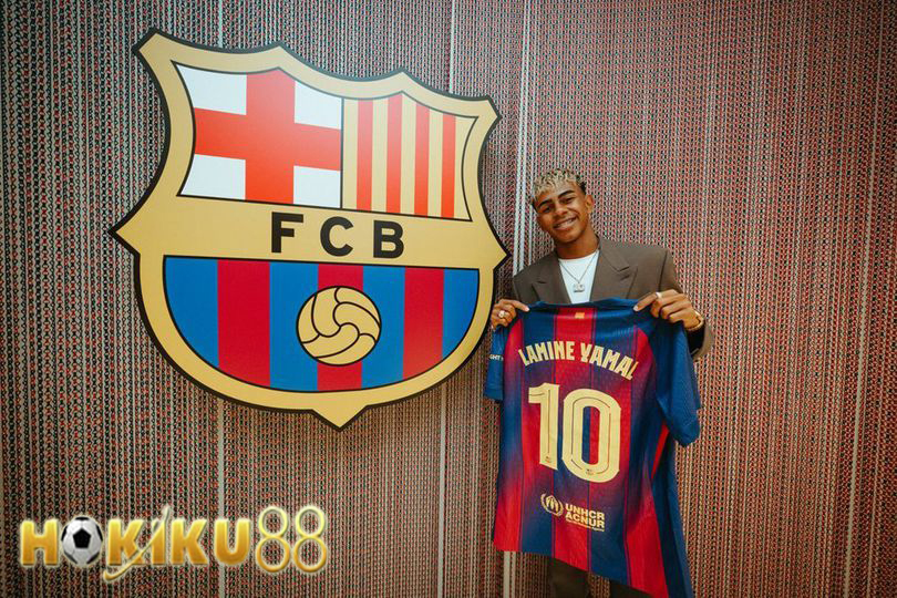 Lamine Yamal memegang jersey nomor 10 Barcelona di depan logo klub, tersenyum bangga sebagai bintang muda baru.